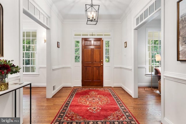  - entryway featuring light wood-style floors, a chandelier, crown molding, and baseboards