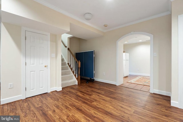  - empty room with wood finished floors, ornamental molding, baseboards, stairs, and arched walkways