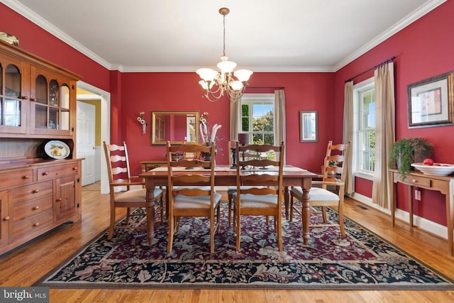  - dining space with a chandelier, wood finished floors, and ornamental molding