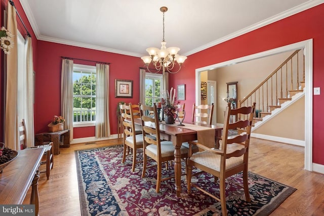  - dining space with a chandelier, crown molding, wood finished floors, and stairway