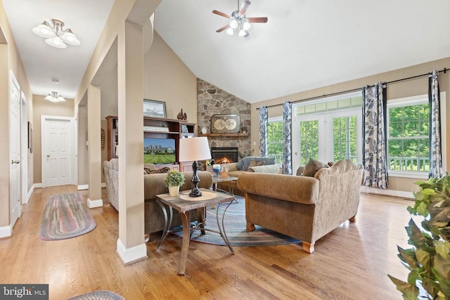  - living room with a stone fireplace, light wood-style flooring, ceiling fan, and high vaulted ceiling