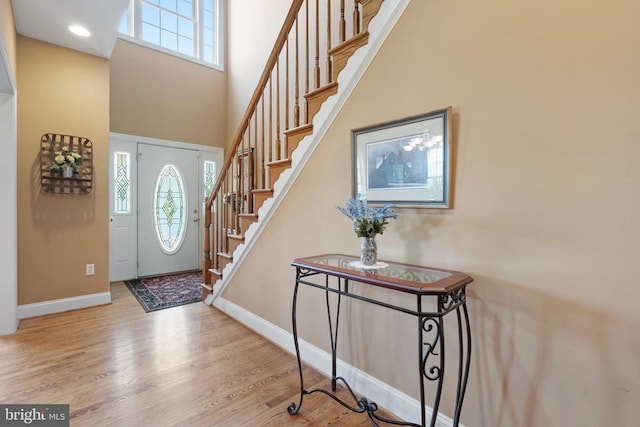  - entrance foyer with plenty of natural light, stairs, a towering ceiling, wood finished floors, and recessed lighting