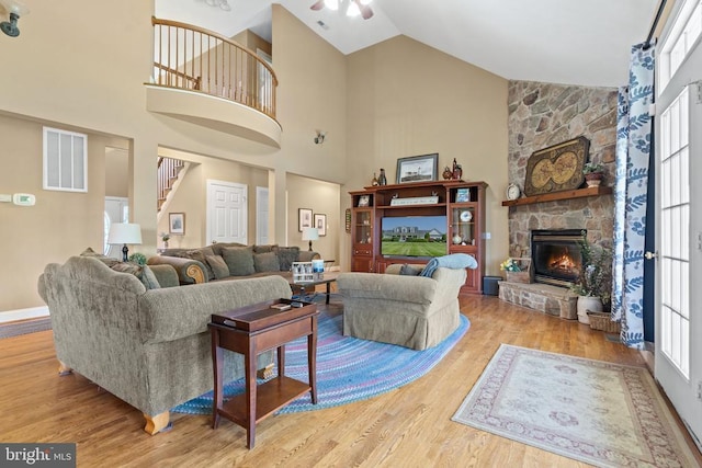  - living room with wood finished floors, a fireplace, ceiling fan, high vaulted ceiling, and stairway