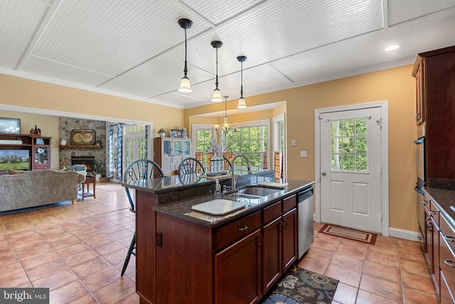  - kitchen with appliances with stainless steel finishes, a breakfast bar area, a stone fireplace, hanging light fixtures, and light tile patterned floors