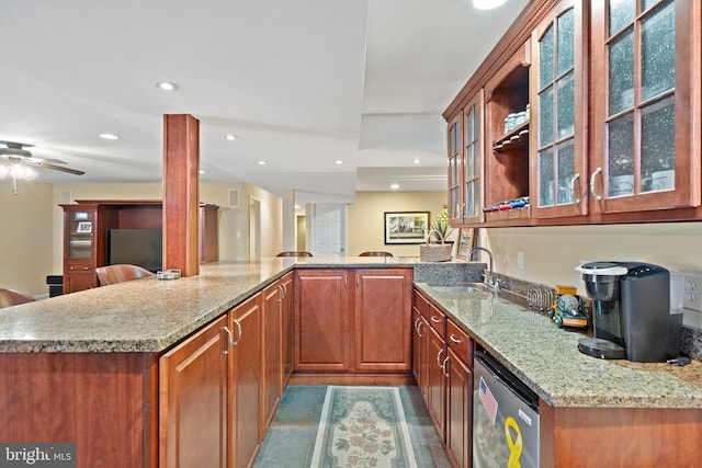  - kitchen featuring light stone counters, dishwashing machine, glass insert cabinets, brown cabinets, and recessed lighting