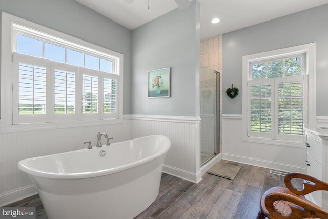  - bathroom featuring a wainscoted wall, wood finished floors, plenty of natural light, a freestanding tub, and a shower stall
