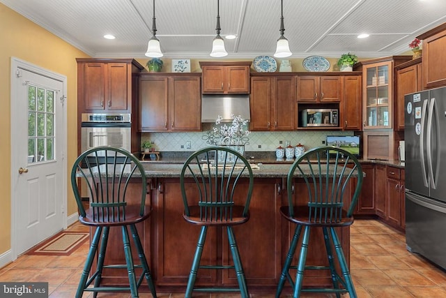  - kitchen with stainless steel appliances, decorative backsplash, a center island with sink, a breakfast bar, and recessed lighting