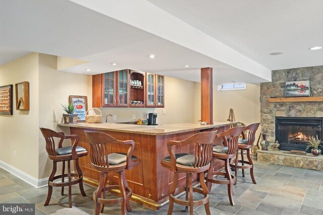  - indoor wet bar featuring stone tile floors, a stone fireplace, and recessed lighting