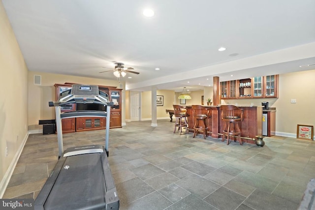  - workout area featuring bar with sink, ceiling fan, recessed lighting, and light stone finish flooring
