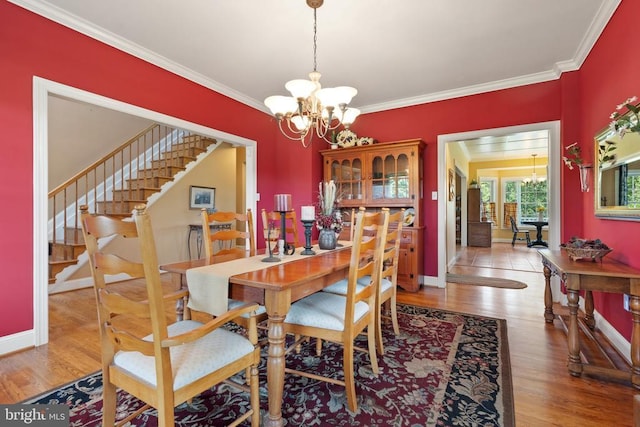  - dining area featuring a chandelier, stairs, crown molding, and wood finished floors