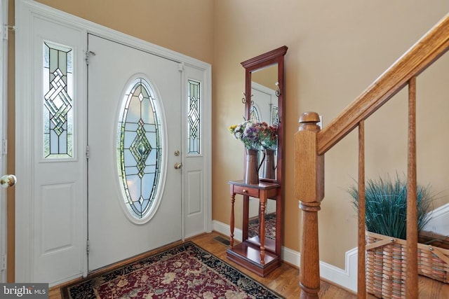  - foyer entrance with plenty of natural light, wood finished floors, and stairs
