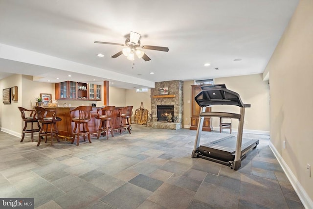  - exercise room featuring a ceiling fan, bar with sink, recessed lighting, a fireplace, and stone finish flooring