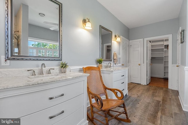  - full bathroom with two vanities, wood finished floors, wainscoting, and a walk in closet