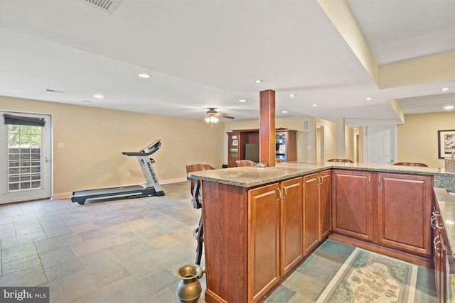  - kitchen with a kitchen breakfast bar, light stone countertops, ceiling fan, recessed lighting, and brown cabinetry
