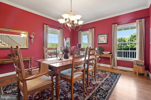  - dining space featuring a chandelier, wood finished floors, crown molding, and stairway