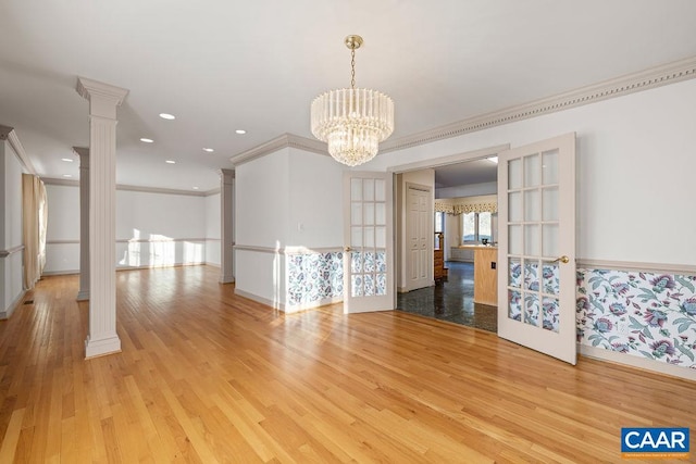 interior space featuring light wood finished floors, ornamental molding, baseboards, and ornate columns