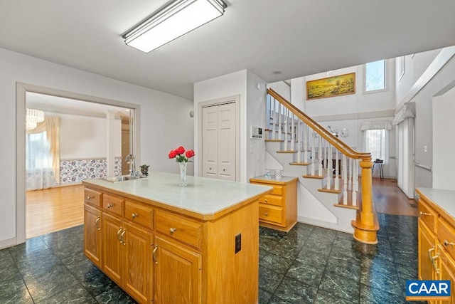 kitchen with a sink, light countertops, a center island, and brown cabinets