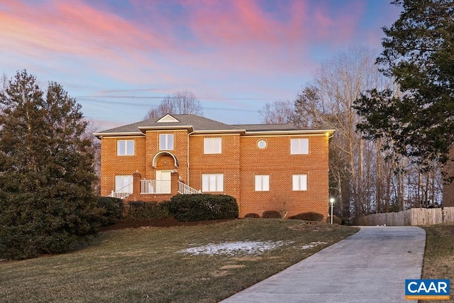 view of front of property with concrete driveway, a yard, and fence