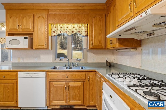 kitchen with under cabinet range hood, light countertops, a sink, and white appliances