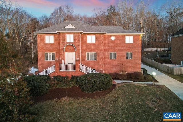 view of front facade featuring fence, a front lawn, and brick siding