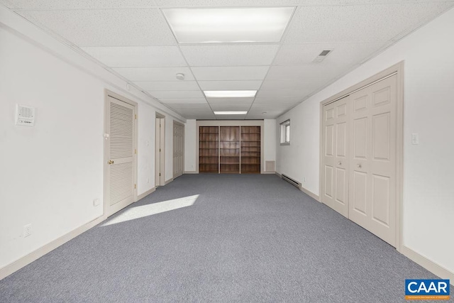 below grade area with baseboards, a drop ceiling, carpet flooring, and baseboard heating