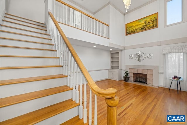 staircase featuring plenty of natural light, a fireplace, baseboards, and a high ceiling