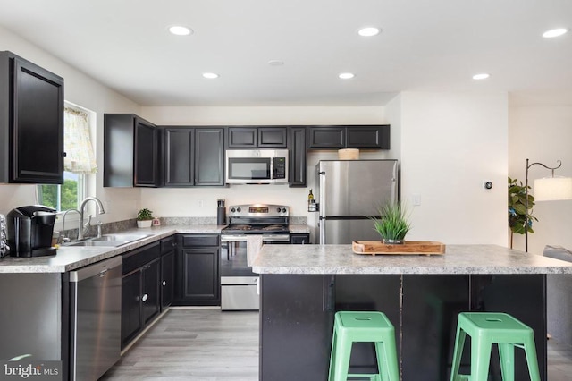 5014 Godwins Landing Dr, Remington, VA 22734 - kitchen with stainless steel appliances, a breakfast bar, recessed lighting, light countertops, and light wood-style flooring