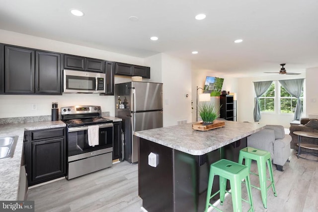 5014 Godwins Landing Dr, Remington, VA 22734 - kitchen featuring appliances with stainless steel finishes, open floor plan, light wood finished floors, a kitchen bar, and light countertops