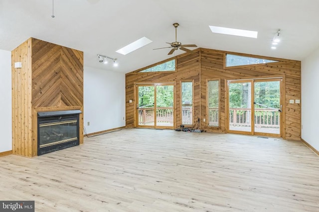 340 Wilson St, Bumpass, VA 23024 - unfurnished living room with a skylight, baseboards, wooden walls, and track lighting