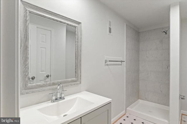 full bath featuring tiled shower and vanity