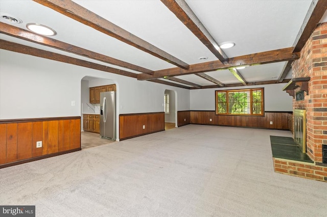 unfurnished living room featuring arched walkways, wood walls, and wainscoting