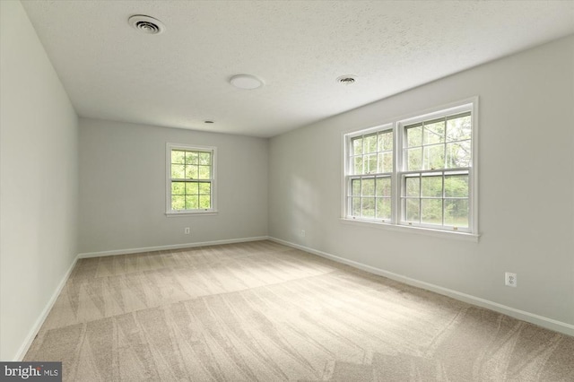 unfurnished room featuring baseboards, carpet flooring, visible vents, and a textured ceiling