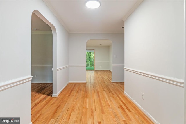 hall featuring arched walkways, wood finished floors, ornamental molding, and baseboards