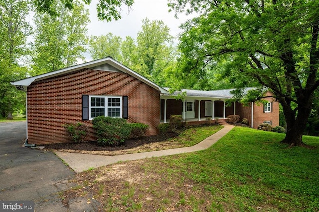 ranch-style home featuring a front lawn, brick siding, and covered porch