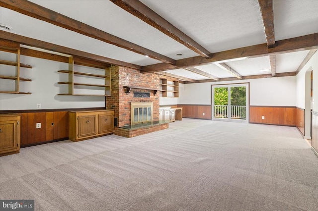 unfurnished living room with light carpet, wooden walls, beamed ceiling, and wainscoting