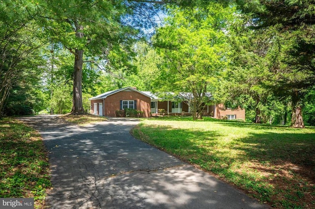 ranch-style home with an attached garage, brick siding, a front yard, and aphalt driveway