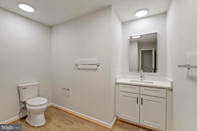 bathroom with wood finished floors, toilet, baseboards, and vanity