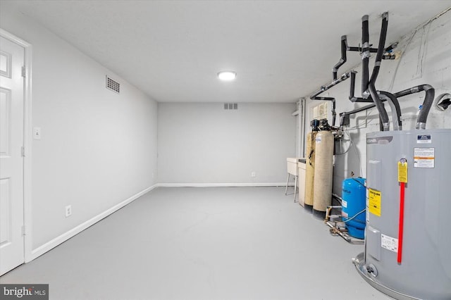 finished below grade area with a water pressure tank, water heater, a water softener system, and baseboards