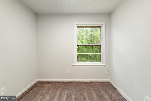 empty room featuring carpet and baseboards