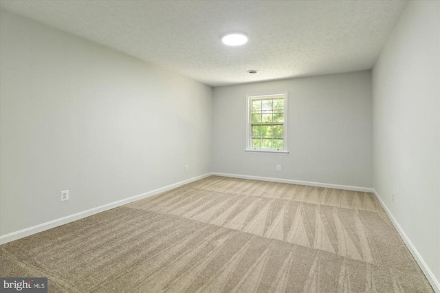 spare room with baseboards, a textured ceiling, and carpet floors