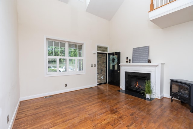 47 Villa View Dr, Staunton, VA 24401 - unfurnished living room featuring high vaulted ceiling, wood finished floors, a fireplace with flush hearth, baseboards, and a wood stove