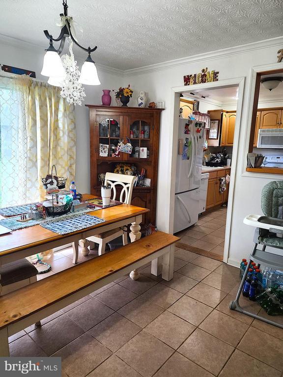 2488 Dry Run Rd, Luray, VA 22835 - dining area featuring light tile patterned flooring, a chandelier, ornamental molding, and a textured ceiling