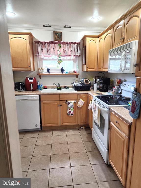 2488 Dry Run Rd, Luray, VA 22835 - kitchen with white appliances, a sink, crown molding, light tile patterned floors, and light countertops