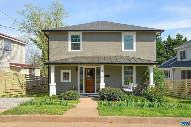 view of front of home featuring stucco siding, fence, a porch, a standing seam roof, and metal roof