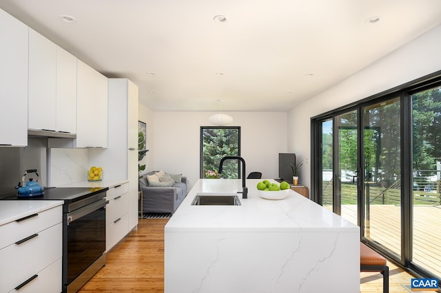 kitchen with a sink, stainless steel electric stove, light wood-style flooring, modern cabinets, and recessed lighting