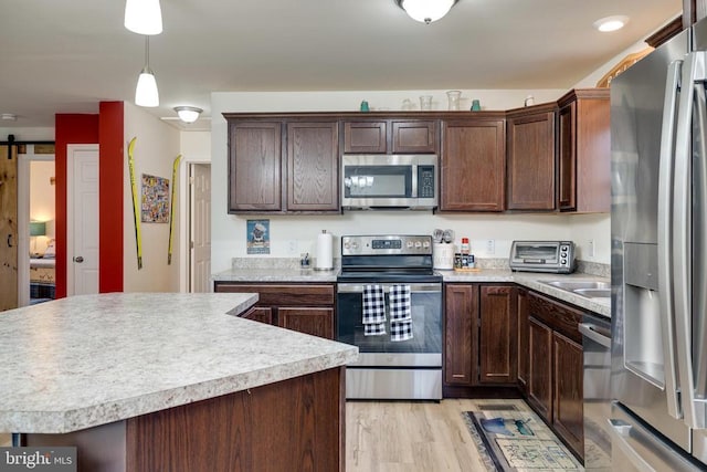 147 Fishermans Ln, Luray, VA 22835 - kitchen with appliances with stainless steel finishes, dark brown cabinetry, light countertops, light wood finished floors, and decorative light fixtures