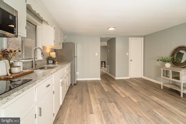 1121 Monacan Trail Rd, Charlottesville, VA 22903 - kitchen featuring a sink, stainless steel appliances, light wood-type flooring, white cabinets, and light stone countertops