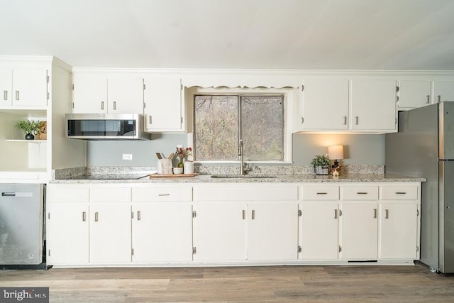 1121 Monacan Trail Rd, Charlottesville, VA 22903 - kitchen featuring a sink, light wood finished floors, white cabinets, light stone countertops, and appliances with stainless steel finishes