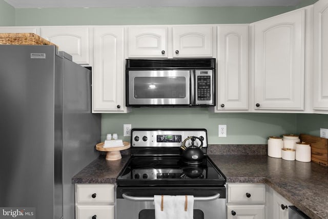  - kitchen featuring stainless steel appliances, dark countertops, and white cabinetry