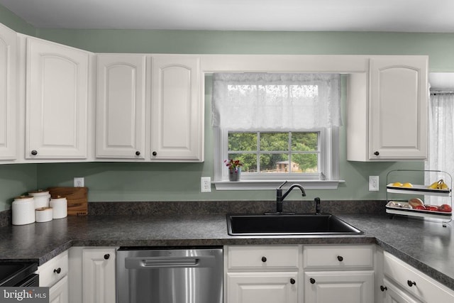  - kitchen with stainless steel dishwasher, dark countertops, and white cabinets